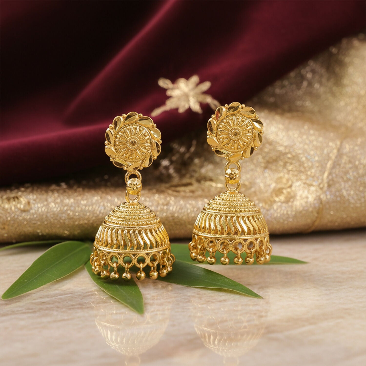 Designer gold plated jhumka earrings showcasing detailed patterns