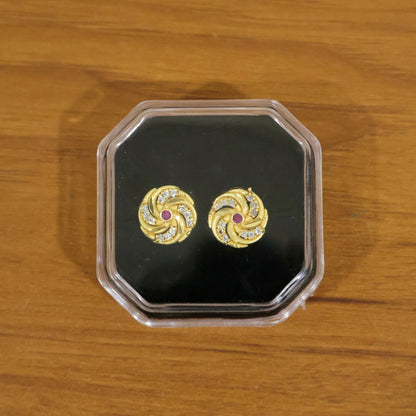 Detailed view of gold spiral stud earrings with sparkling red stones