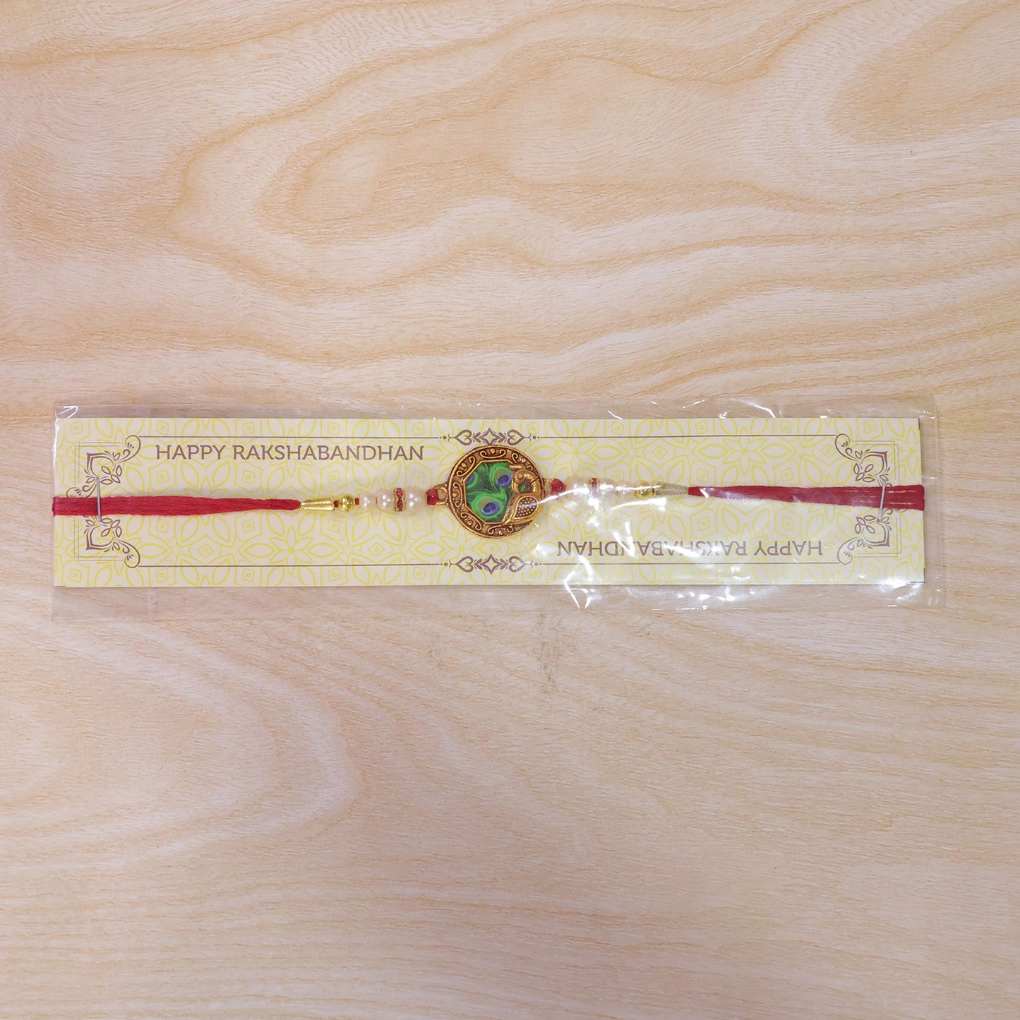 Peacock Feather Rakhi – Elegant Pearl Bead Accents on Red Thread