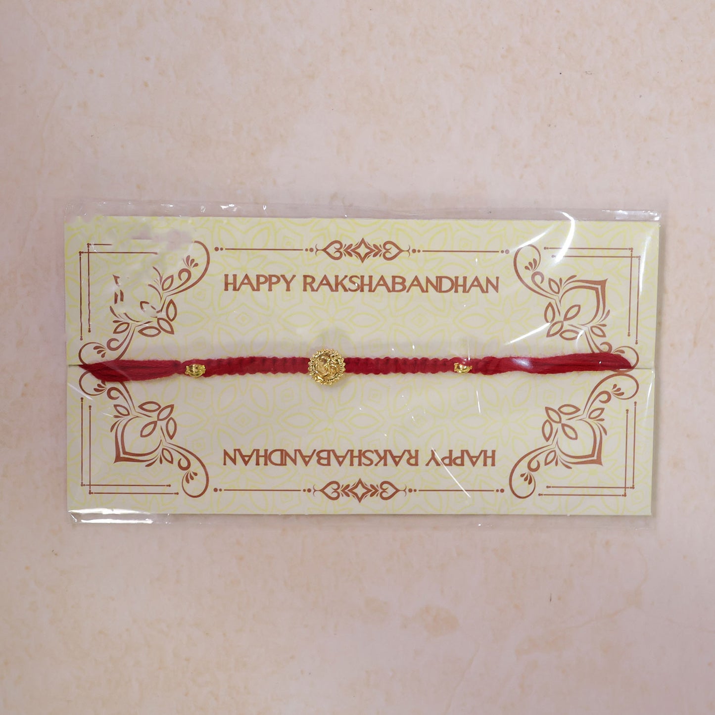 Red Thread Rakhi with an Antique Gold Om Pendant and Beaded Accents