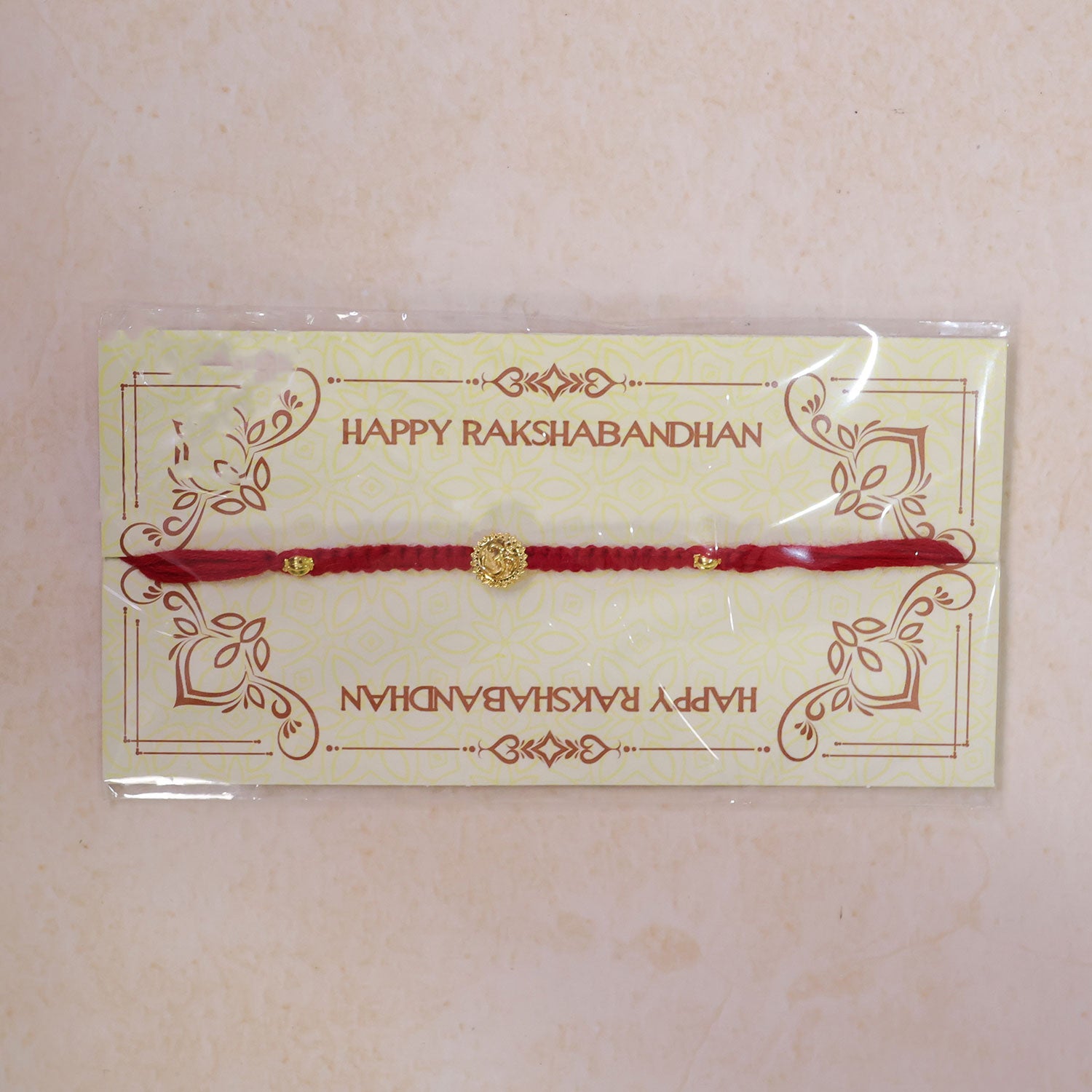 Red Thread Rakhi with an Antique Gold Om Pendant and Beaded Accents
