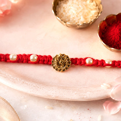 Red Braided Rakhi with Antique Gold Om Pendant and Lustrous Pearls