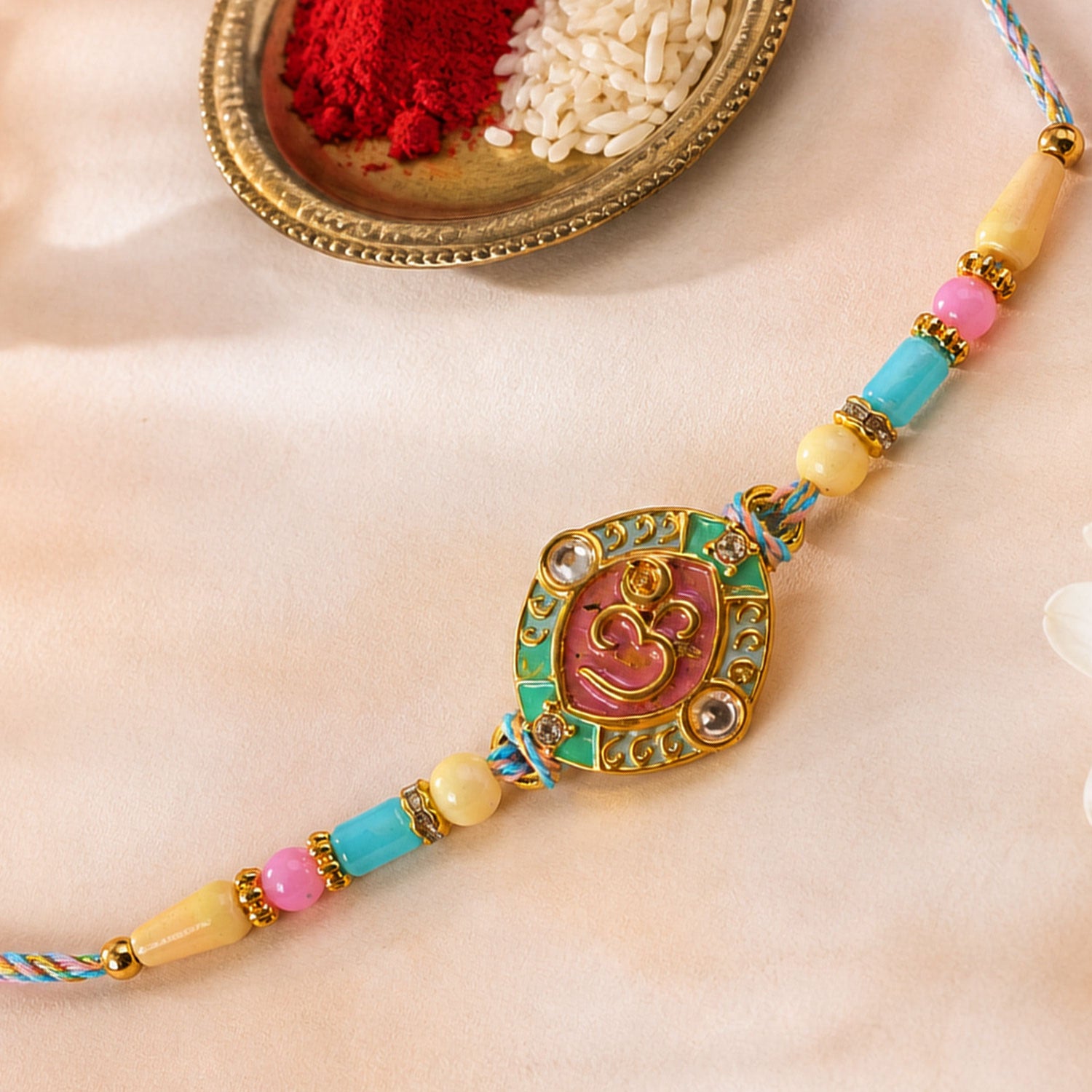 Turquoise Om Pendant Rakhi with Pink Kundan and Pastel Beads