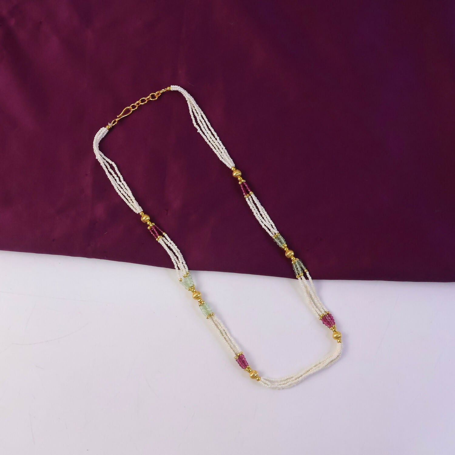 Close-up of pearl and colored beads with gold detailing on mala necklace