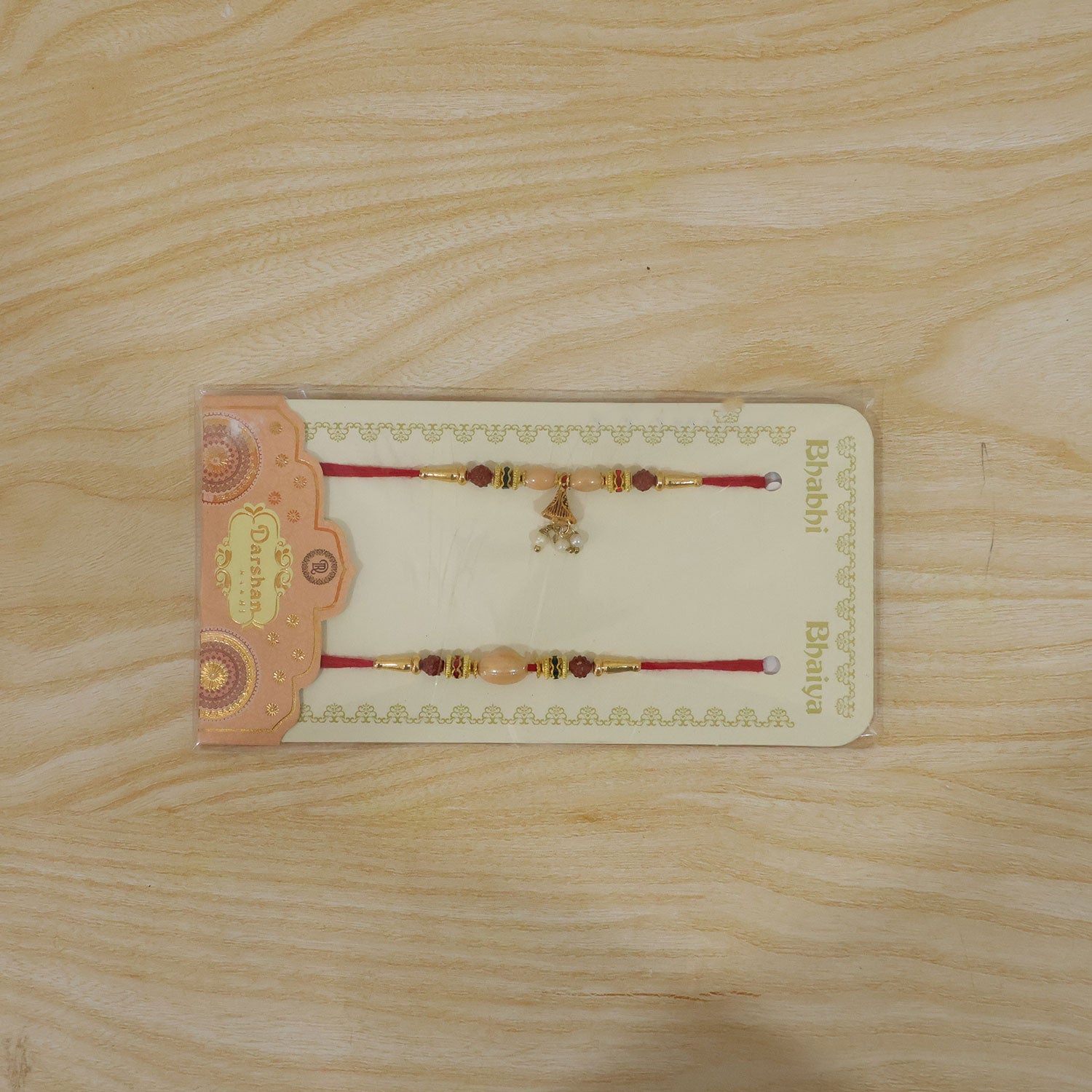 Couple Rakhi with Peach Oval Center Bead and Pearl Drop Charm