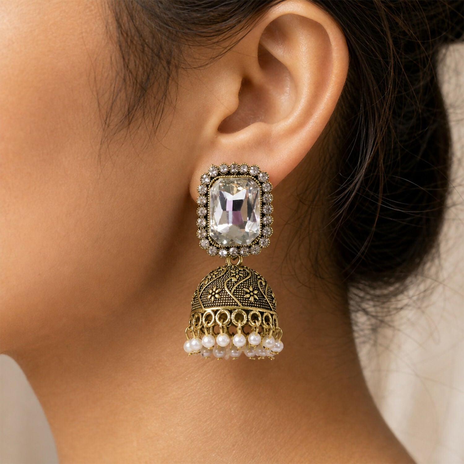 Side view of antique gold white stone jhumka earrings with pearl-style drops