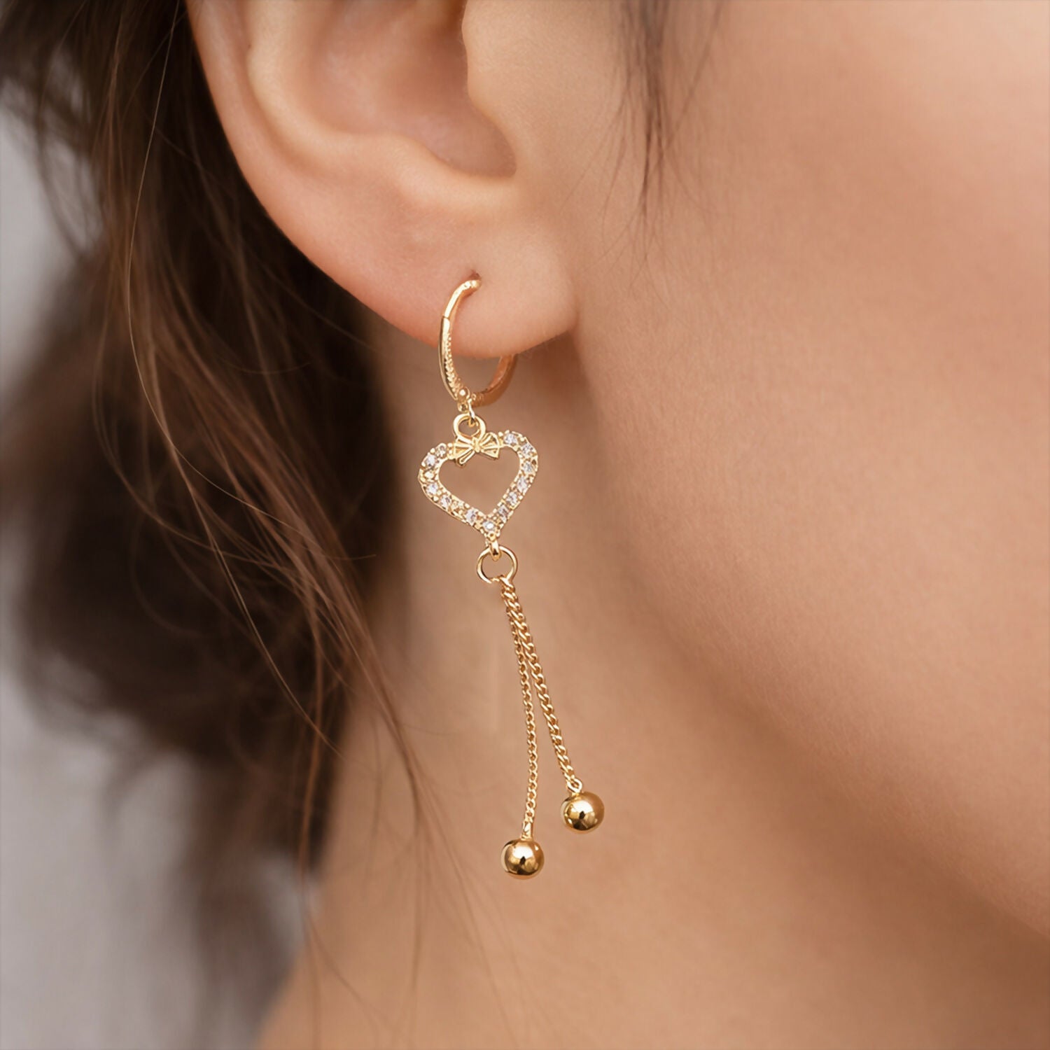 Close-up of heart shape earrings showing sparkling stones and delicate chain tassels