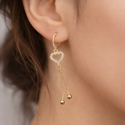 Close-up of heart shape earrings showing sparkling stones and delicate chain tassels