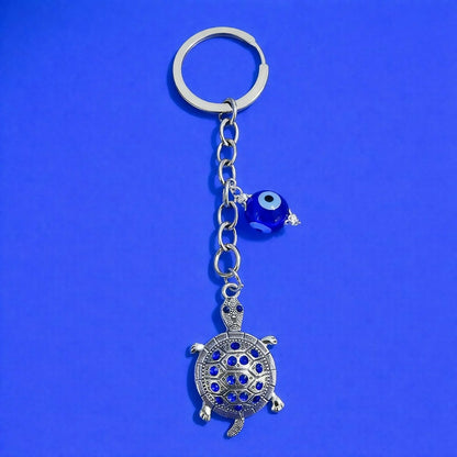 Close-up of turtle keychain with decorative evil eye pendant