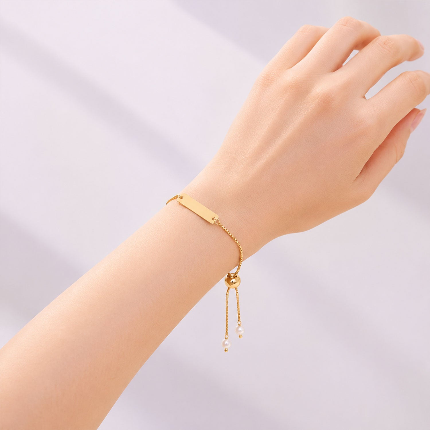 Close up of the gold tone nameplate on the custom bracelet with pearl details.