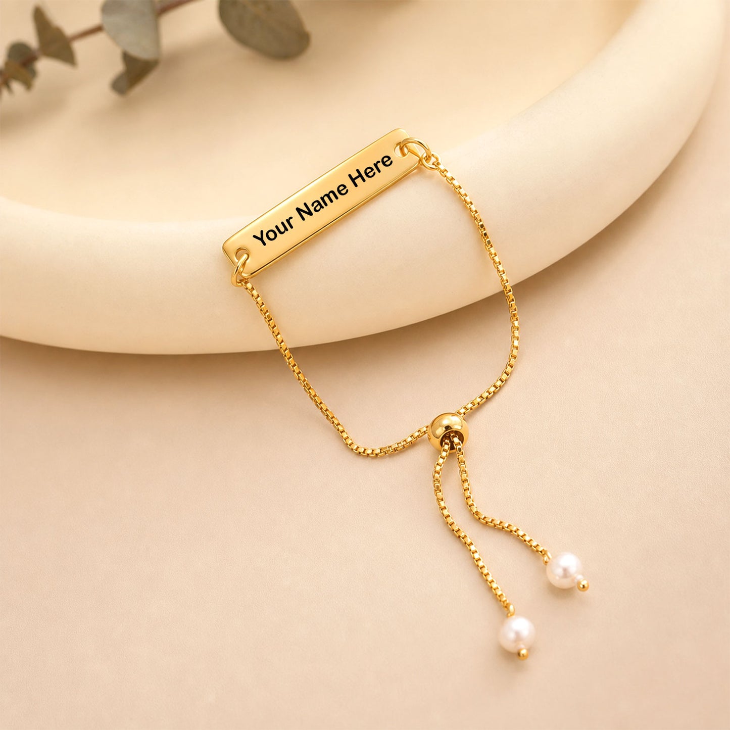 Personalised gold tone bracelet featuring engraved nameplate and pearl accents.