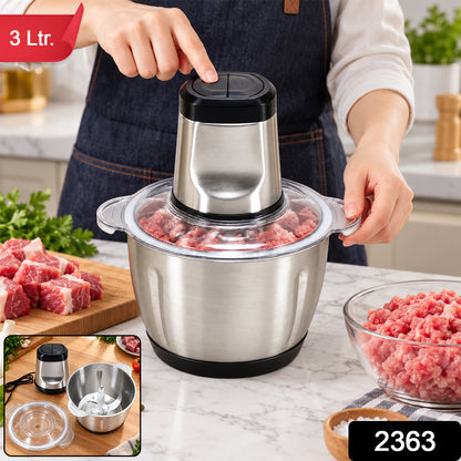 A person's hands operating a stainless steel electric food chopper with raw meat, garlic, and spices on a kitchen counter.