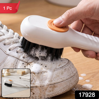 A person uses a white and orange scrubbing brush to clean a dirty white sneaker, creating soap suds.