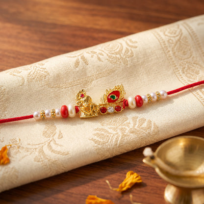 Krishna Mor Pankh Rakhi with Red Pearls and Festive Gold Charm