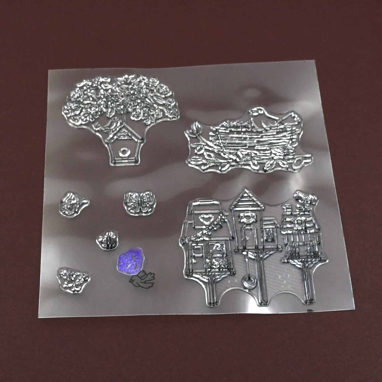 A clear rubber stamp sheet features detailed designs of a tree, bird's nest, and multiple birdhouses.