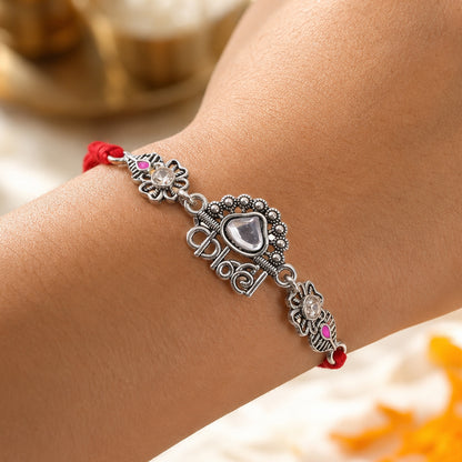 Silver-Toned Kanha Rakhi with Kundan-Style Stone, Crystal Accents & Designer Red Thread