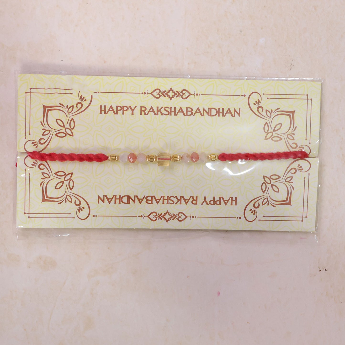 Red Thread Rakhi with Peach and Rose-Toned Crystal Bead Pendant