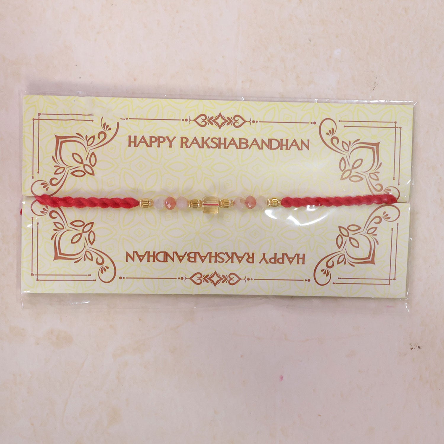 Red Thread Rakhi with Peach and Rose-Toned Crystal Bead Pendant