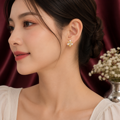 A woman wearing a white top with a gold-plated floral stud earring with crystals and mini pearls on her right ear.