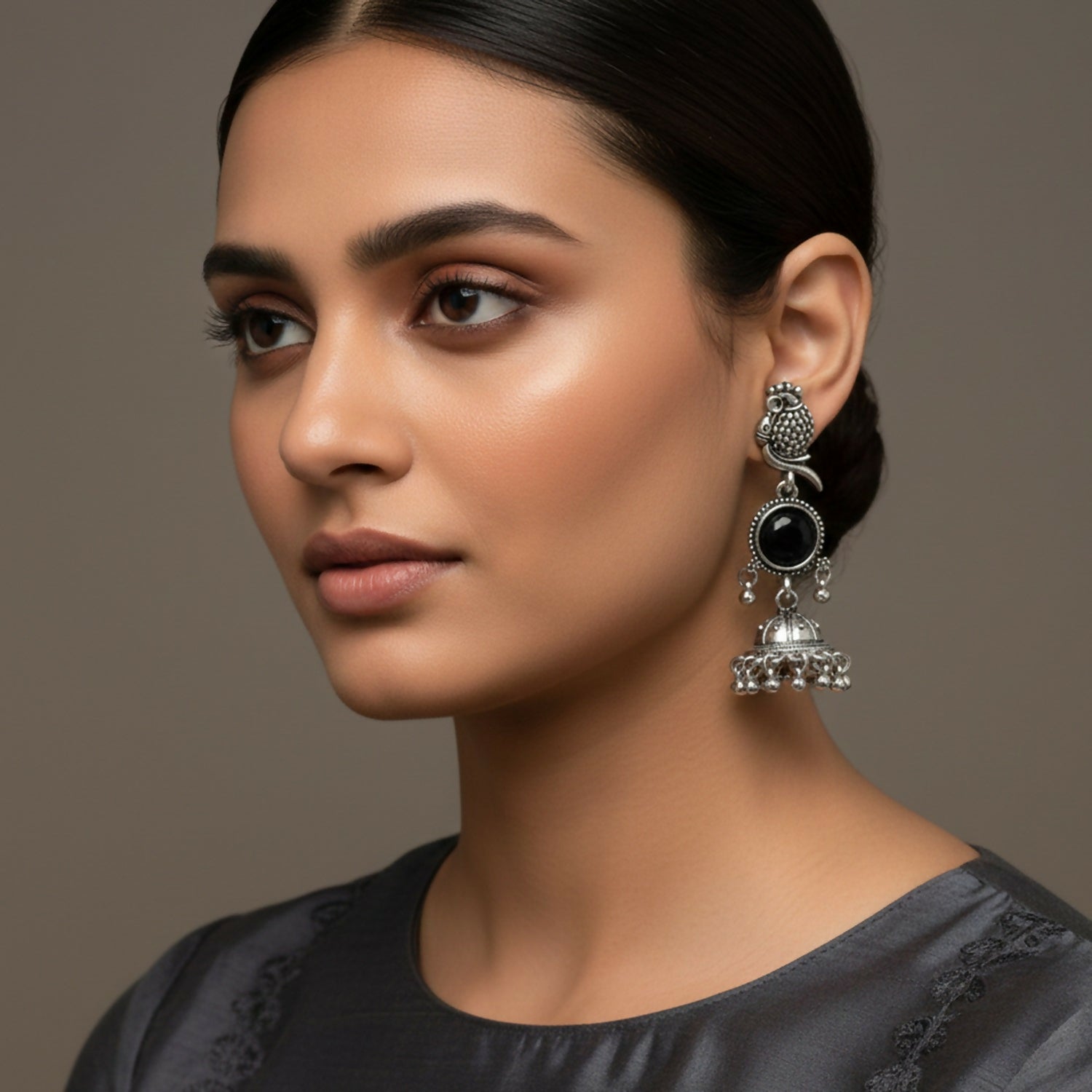 Close-up of oxidized silver jhumka earrings showing detailed owl stud and black stone centerpiece