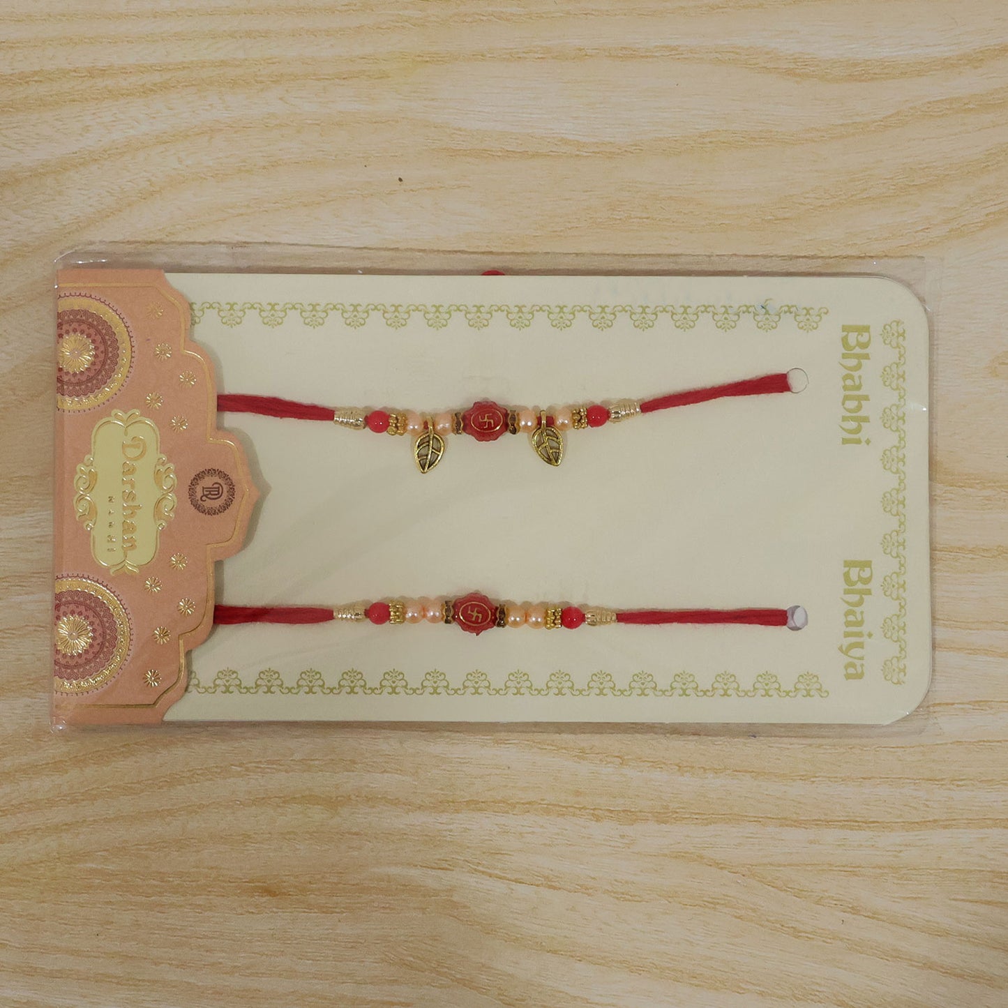 Couple Om Rakhi Set with Red Beads, Golden Leaf Charms and Festive Lumba Pair Design