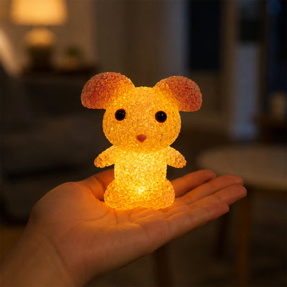 A yellow mouse-shaped crystal texture LED lamp glowing in the palm of a hand in a dimly lit room.