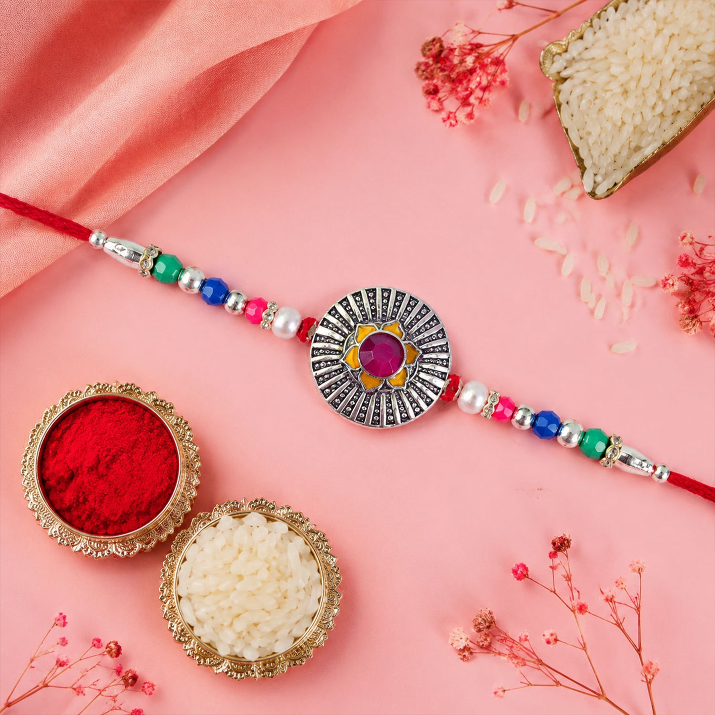 Sunburst Stone Rakhi with Magenta Centre, Pearl Beads, Roli Chawal Coin and Card Packing