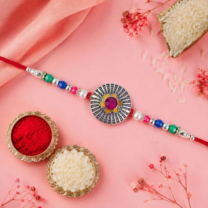 Sunburst Stone Rakhi with Magenta Centre, Pearl Beads, Roli Chawal Coin and Card Packing