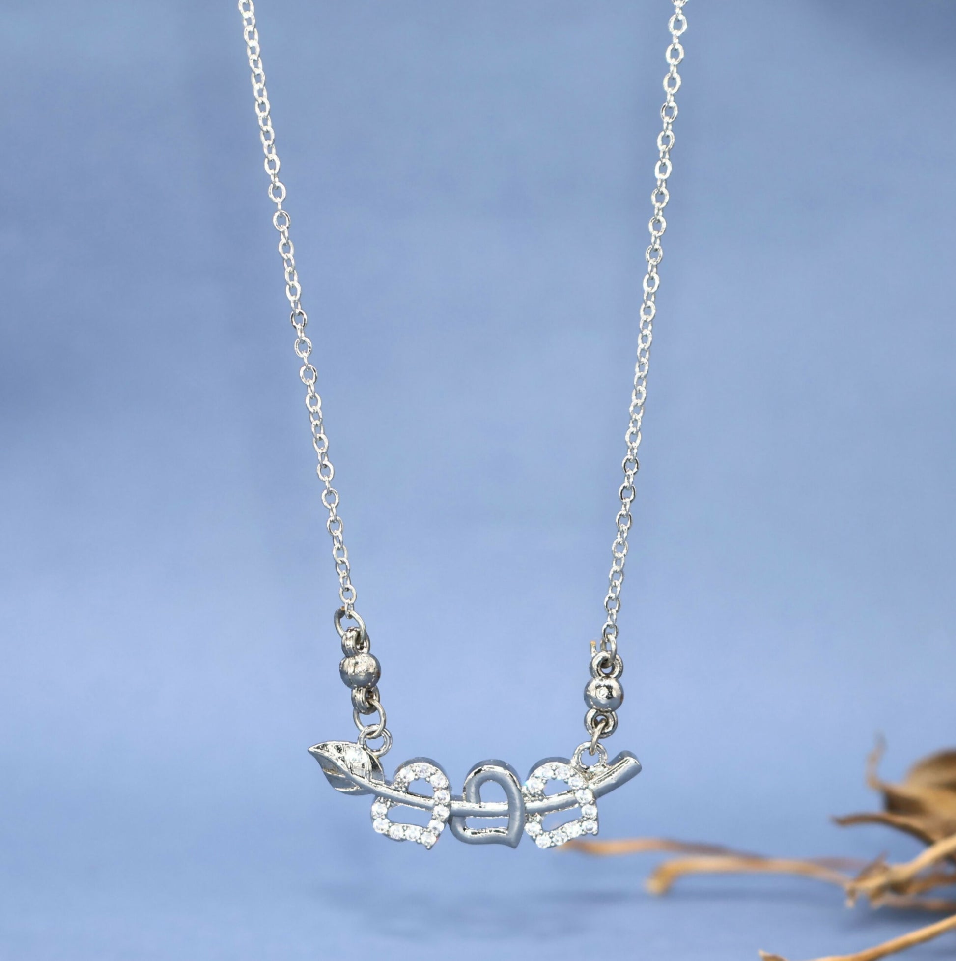 Close-up of silver tone double heart pendant pierced by Cupid's arrow with sparkling CZ stones