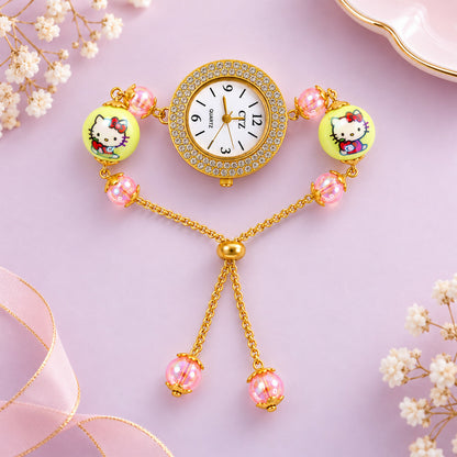 A gold-tone bracelet watch with a rhinestone-adorned dial, two large yellow beads with cartoon characters, and smaller pink