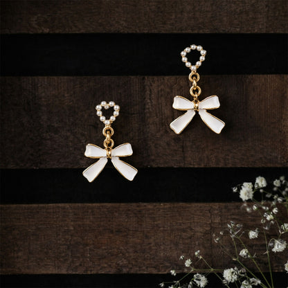 Pearl heart and bow earrings displayed with subtle shadows