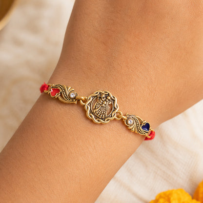 Antique Gold-Toned Radha Krishna Rakhi with Crystal Accents, Enamel Hearts & Red Thread