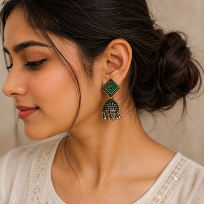 Side profile of an oxidised peacock feather jhumka earring highlighting its dome shape.