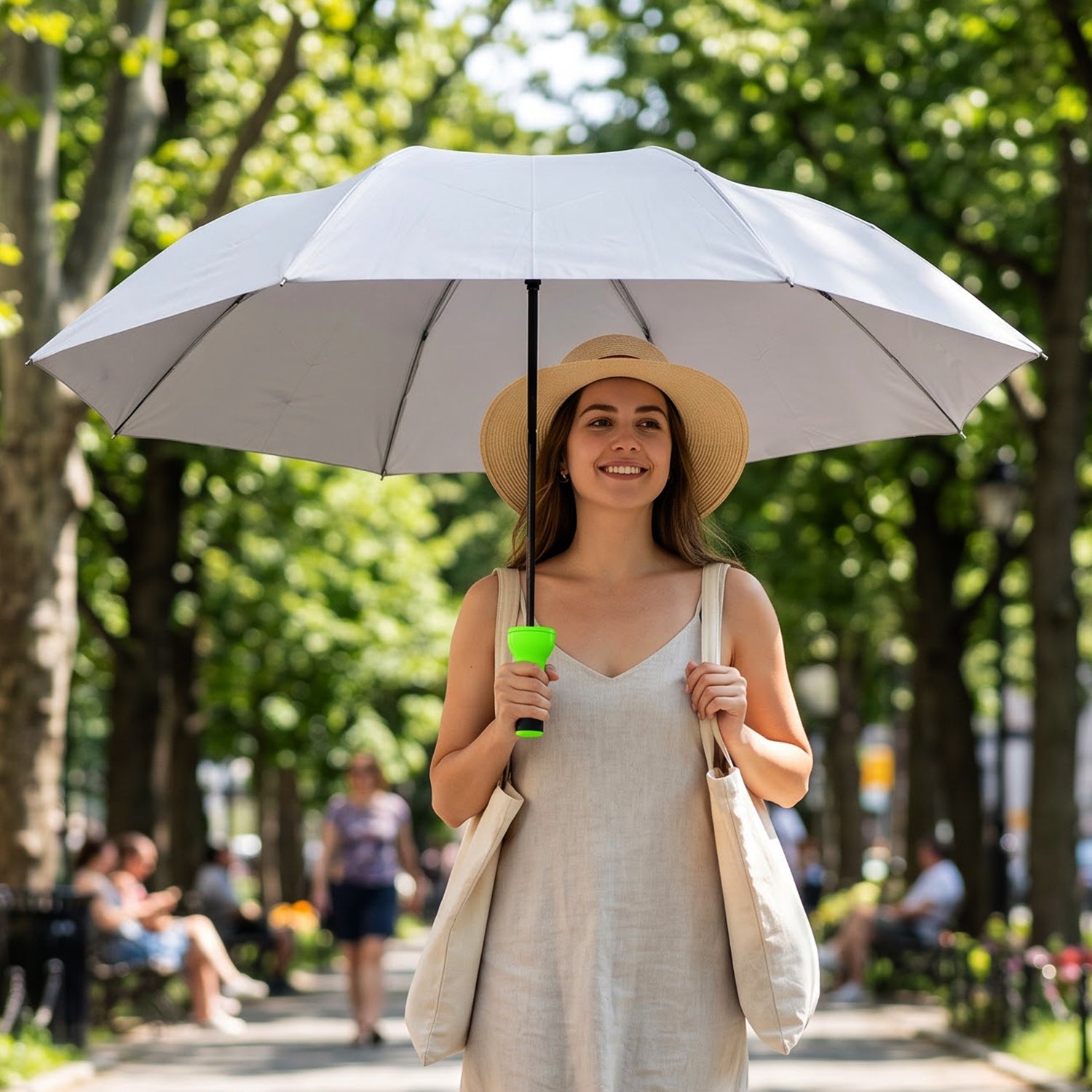 Woman holding a large grey umbrella with a bright green handle while walking in a park, with people in background.