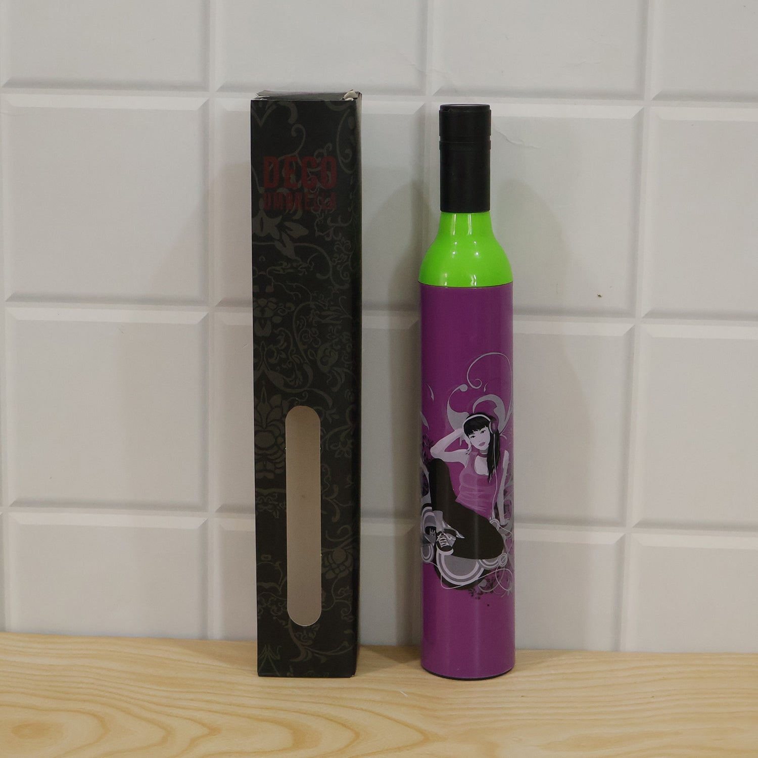 Purple umbrella case shaped like a wine bottle with a woman illustration, next to a black patterned box.