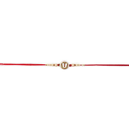 A red devotional thread with a central white and gold charm, adorned with small pearls and beads, is centered against a