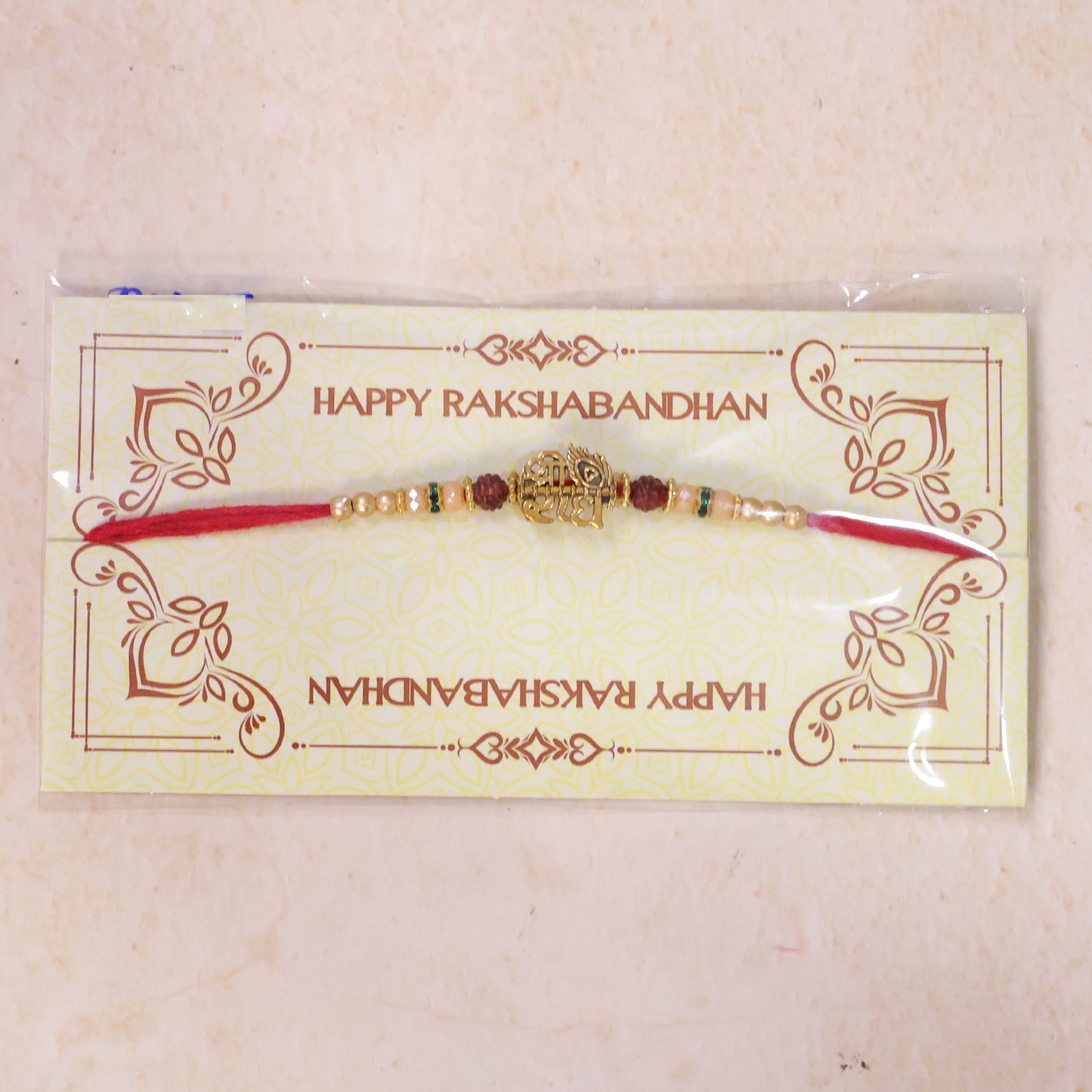Red Thread Rakhi with Antique Gold Radhe Pendant and Peacock Feather