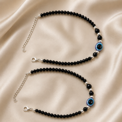 Close-up of the black evil eye anklet showing bead and charm details.