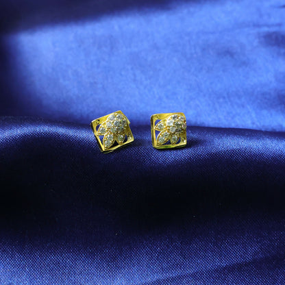Detailed view of floral design on gold stud earrings with sparkling stones