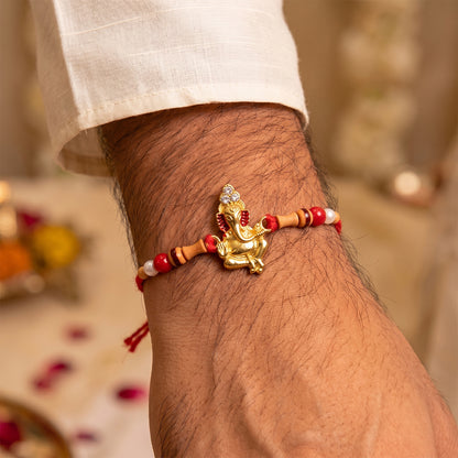Golden Ganesha Rakhi with Peach Beads and Pearl Accents