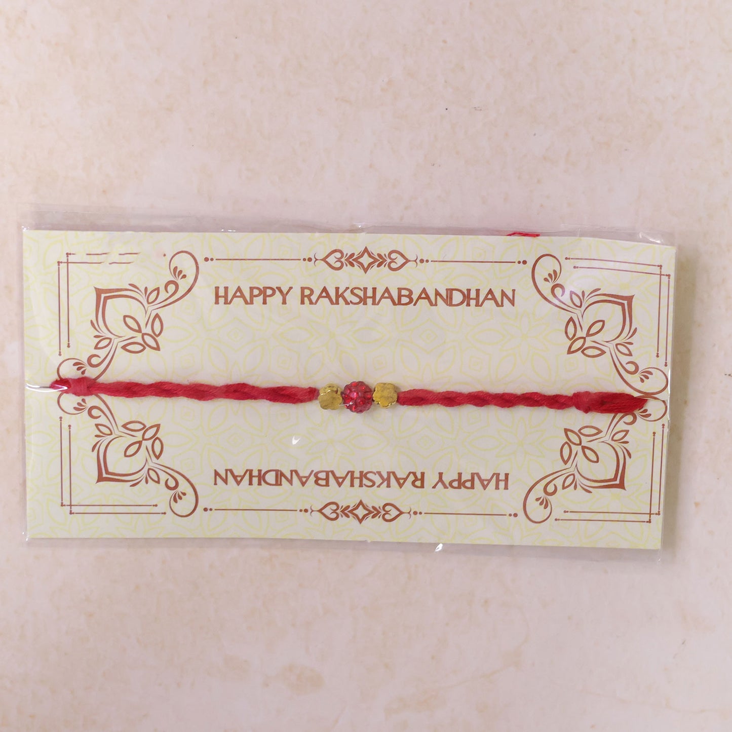 Red Thread Rakhi with Sparkling Red Ball Bead and Gold Flower Accents