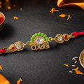 Gold-Toned Kanha Rakhi with Kundan-Style Stone, Green Enamel, Crystal Accents & Red Thread