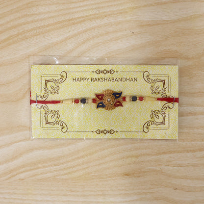 Gold Sunburst Rakhi with Blue Red Beads and Pearl Accents