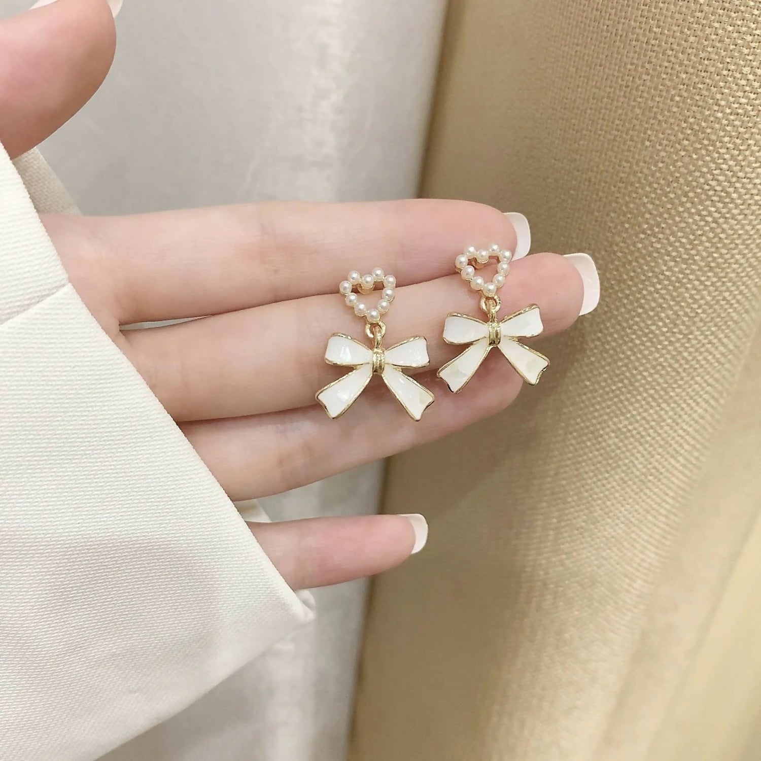 Side view of vintage-inspired pearl heart and bow earrings