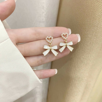 Side view of vintage-inspired pearl heart and bow earrings