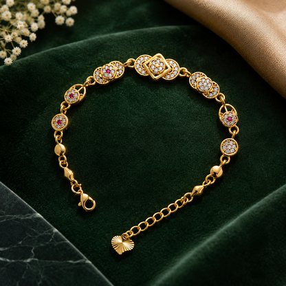 A gold-plated bracelet with alternating clear and red cubic zirconia stones, displayed on a dark green velvet background.