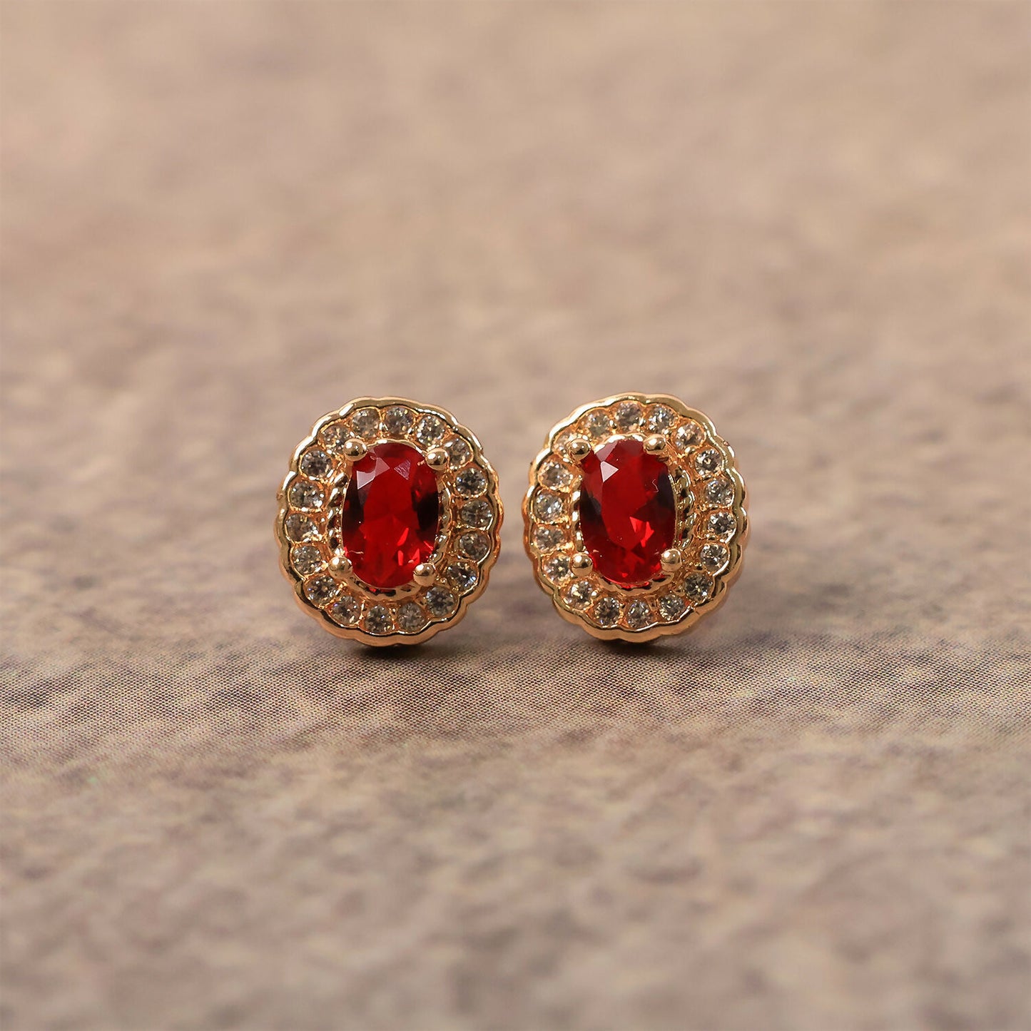 Side view of red stone stud earrings with elegant crystal halo and golden setting