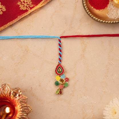 Close-up of traditional meenakari rakhi with blue thread