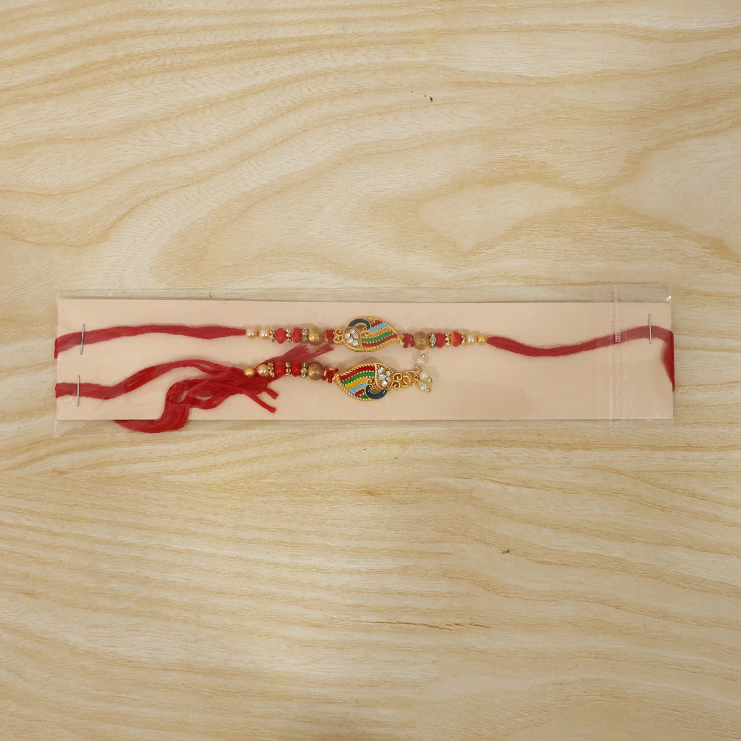 Traditional Peacock Meenakari Rakhi with pearl beads on plain background