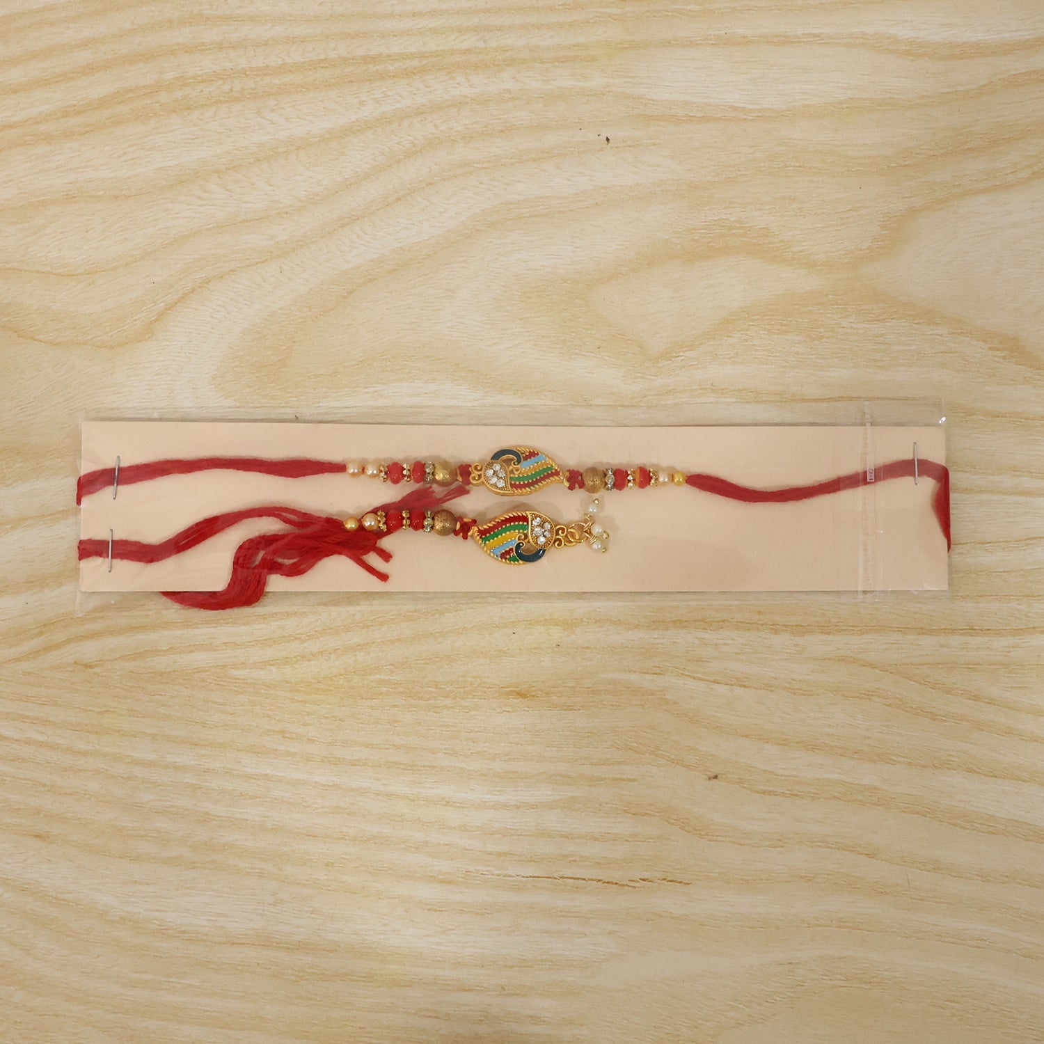 Traditional Peacock Meenakari Rakhi with pearl beads on plain background